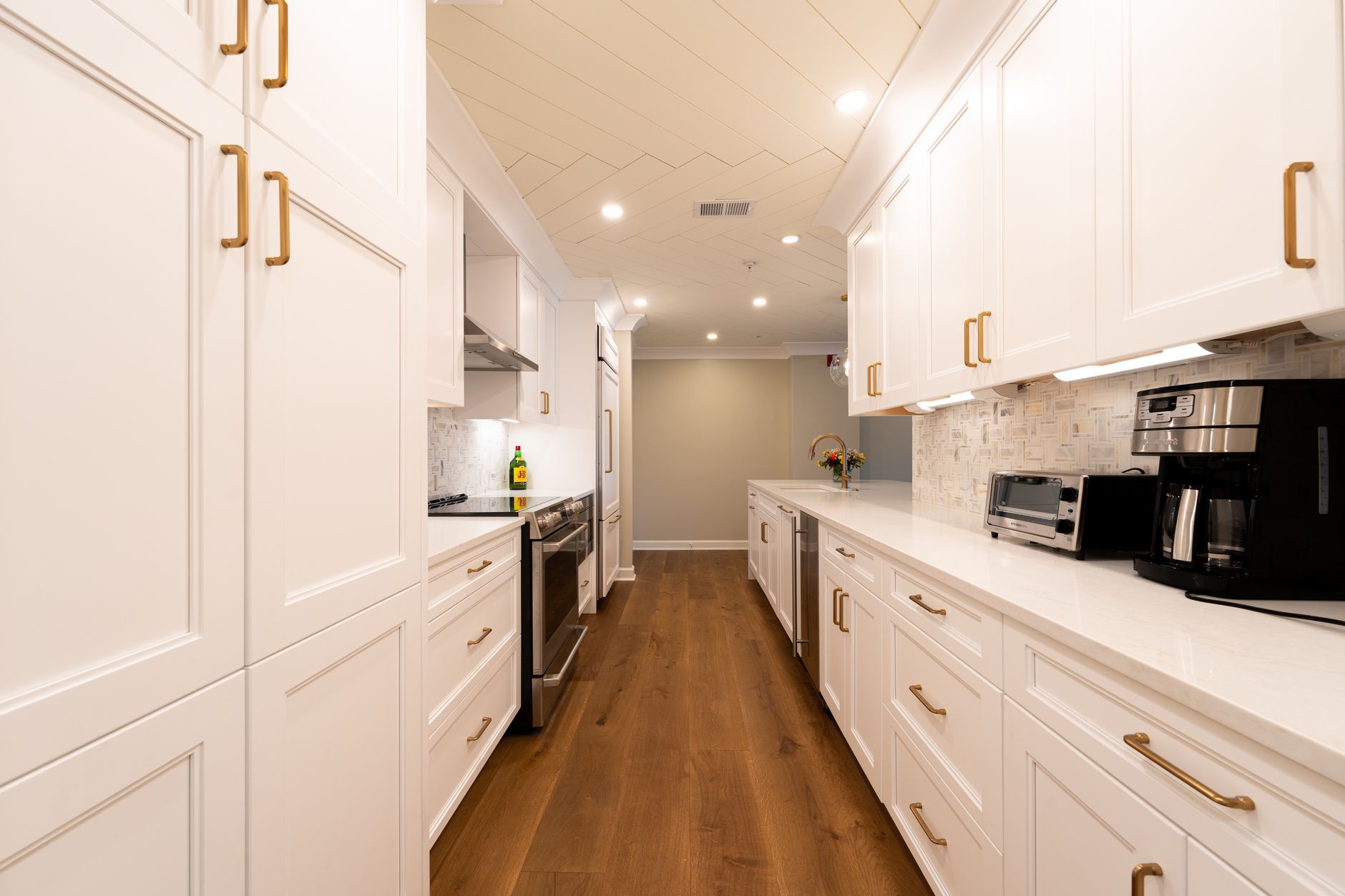 Finished galley kitchen with white modular cabinets and brass hardware