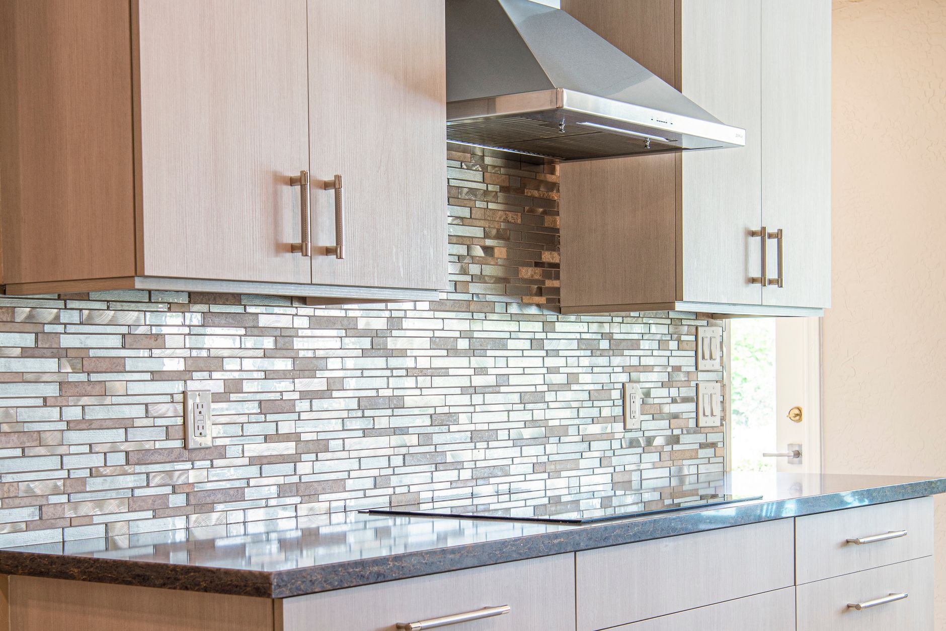 Kitchen with mosaic backsplash and stainless range hood