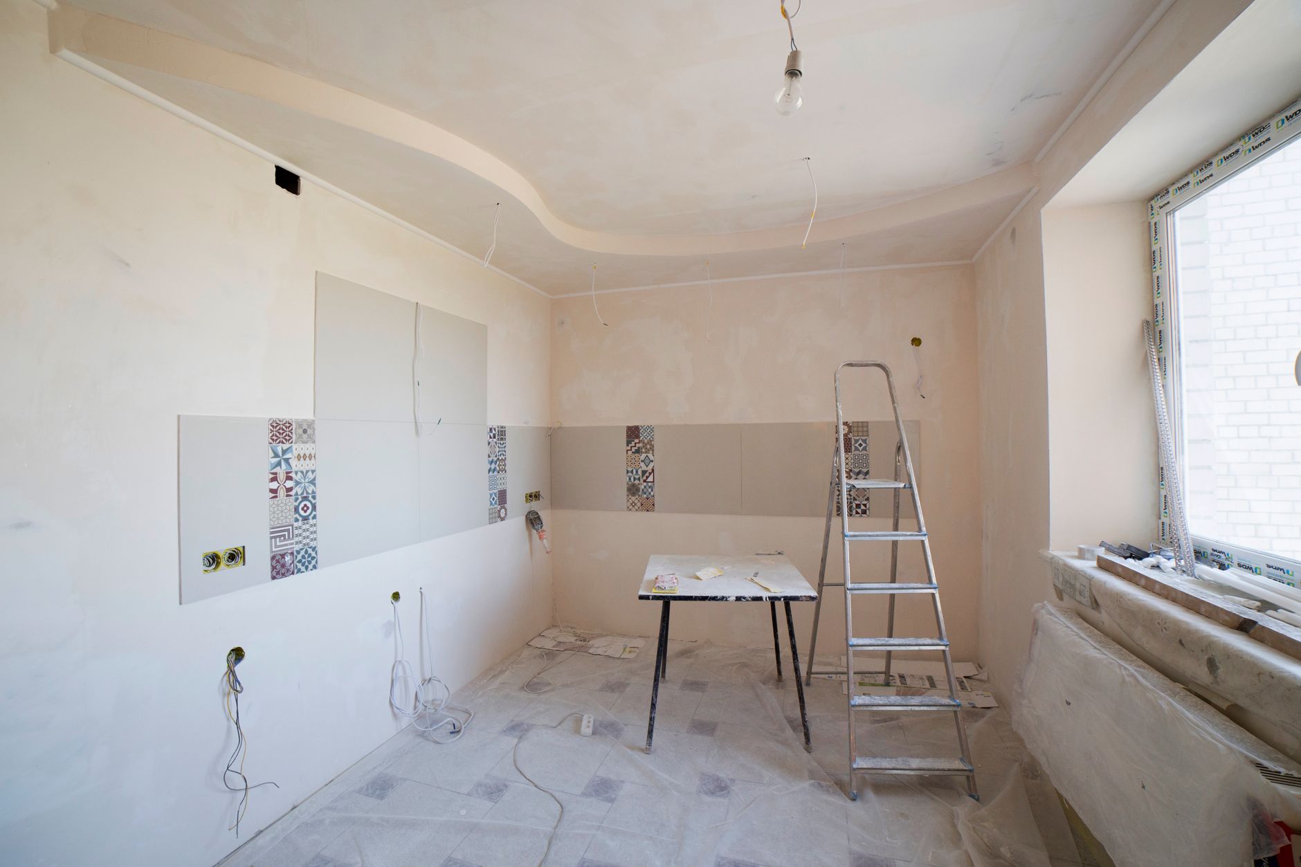 Same kitchen area during construction, bare plaster and exposed wiring